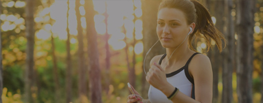 Frau joggt mit Kopfhörern durch den Wald