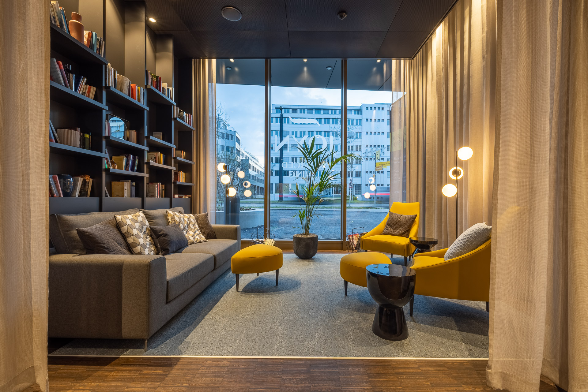 A view of the modern lobby with comfortable seating and a large bookshelf at JOYN Zurich.